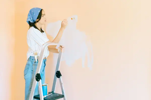 Interior painting in Oceanside: painter on a stepladder rolling a wall